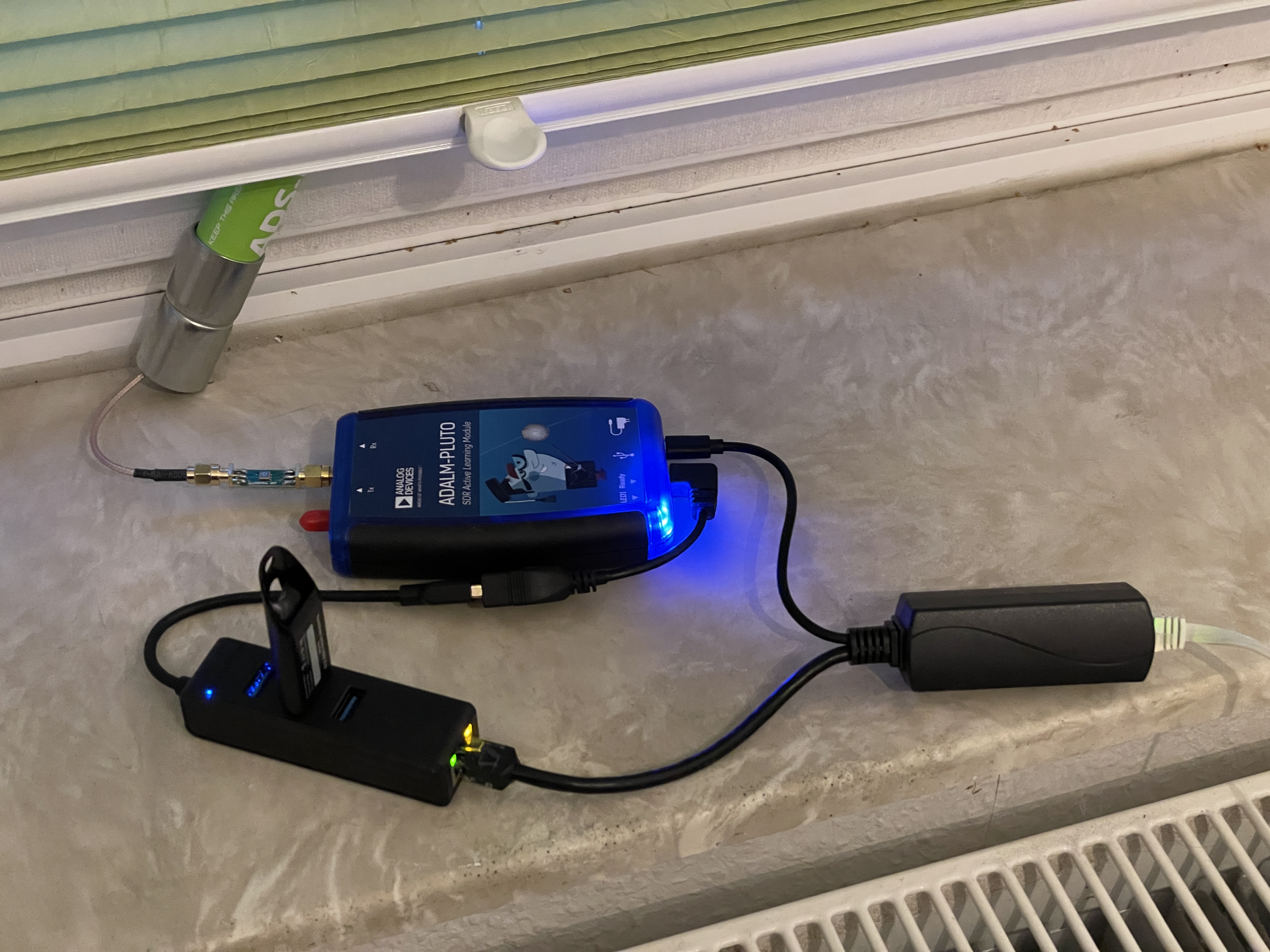 Setup on a windowsill, PlutoSDR with external ADSB antenna, 1090 MHz band pass filter, PoE-extractor and USB hub/USB ethernet card combo